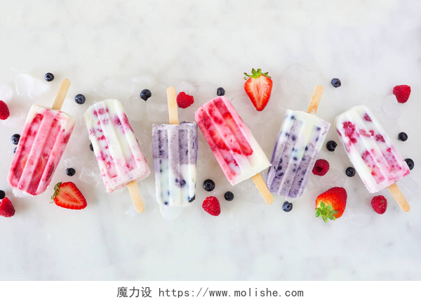 桌子上各种各样的冰棍一组不同种类的浆果、水果、酸奶、冰块。白色大理石背景上一排的顶视图.